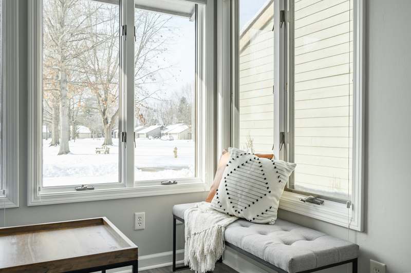 Cozy home office corner with a white-painted wooden daybed used as both seating and guest bed